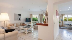 A modern living room with a sofa, coffee table, TV, and artwork.