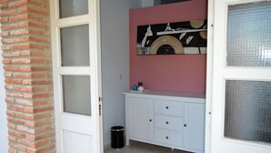 A room with a white door, a brick wall, a white cabinet with drawers, and a pink wall with a decorative plate. - House 4 Mar y Arena. Villa with private pool and all possible extras. (Barbate Cadiz)