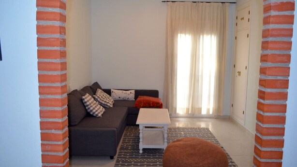 Ein Wohnzimmer mit einer Couch, einem kleinen Tisch und einem gemusterten Teppich.