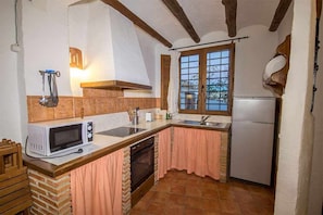 Een kleine keuken met een magnetron, spoelbak en oven.