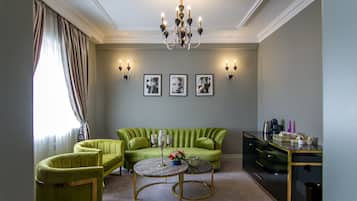 A living room with a green sofa, two armchairs, a coffee table, and a TV stand.