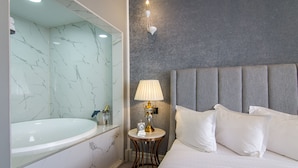A hotel room with a marble bathroom, a bed with white linens, and a bedside table with a lamp. - Lido by Phoenicia (Bucharest)