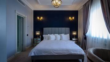 Una cama grande con cabecera gris, dos lámparas de noche y un candelabro.