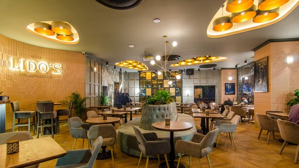 A restaurant interior with round tables, cushioned seating, and modern pendant lighting. - Lido by Phoenicia (Bucharest)