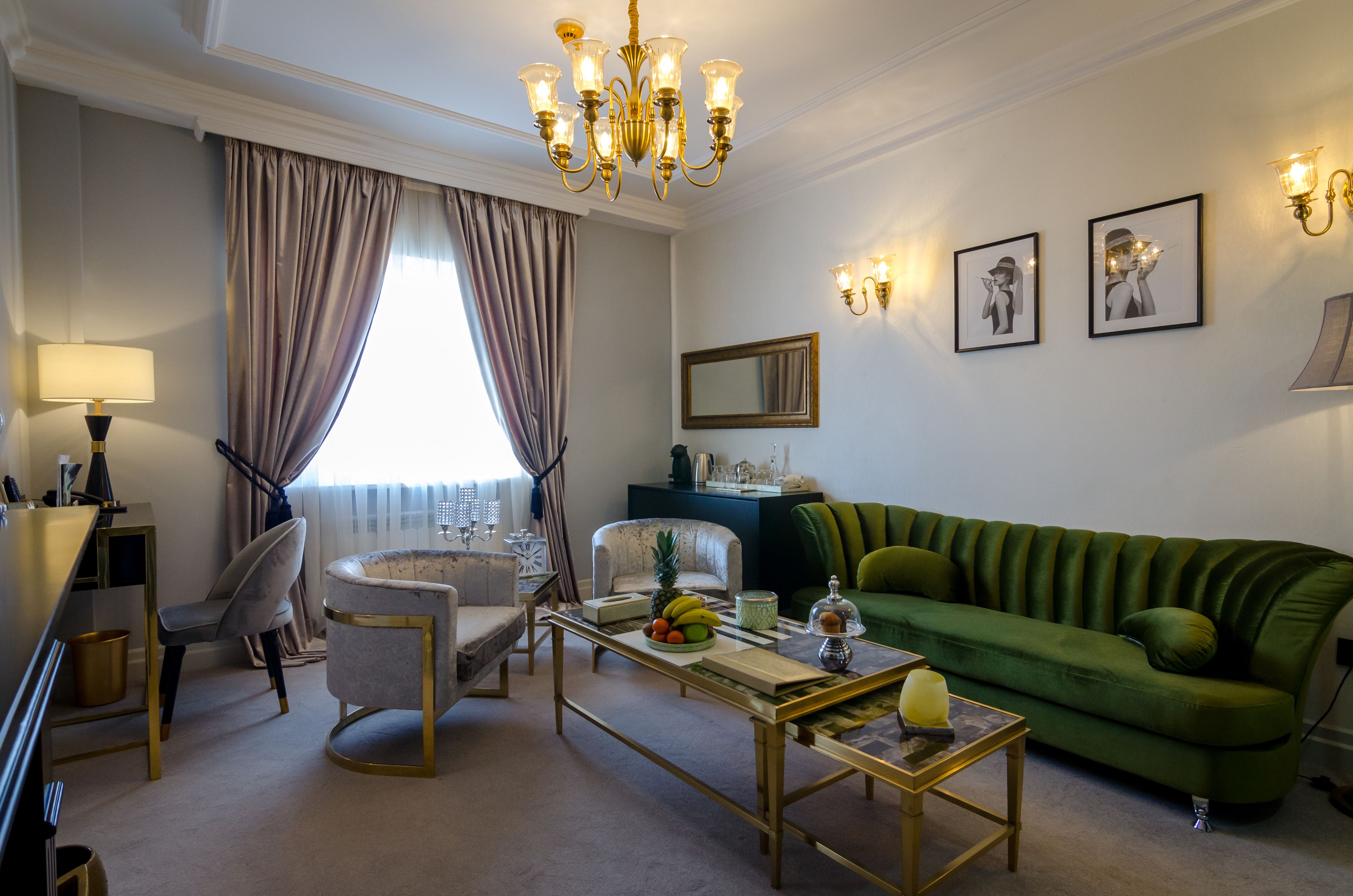 A well-lit living room with a green sofa, a dining table, and a chandelier.