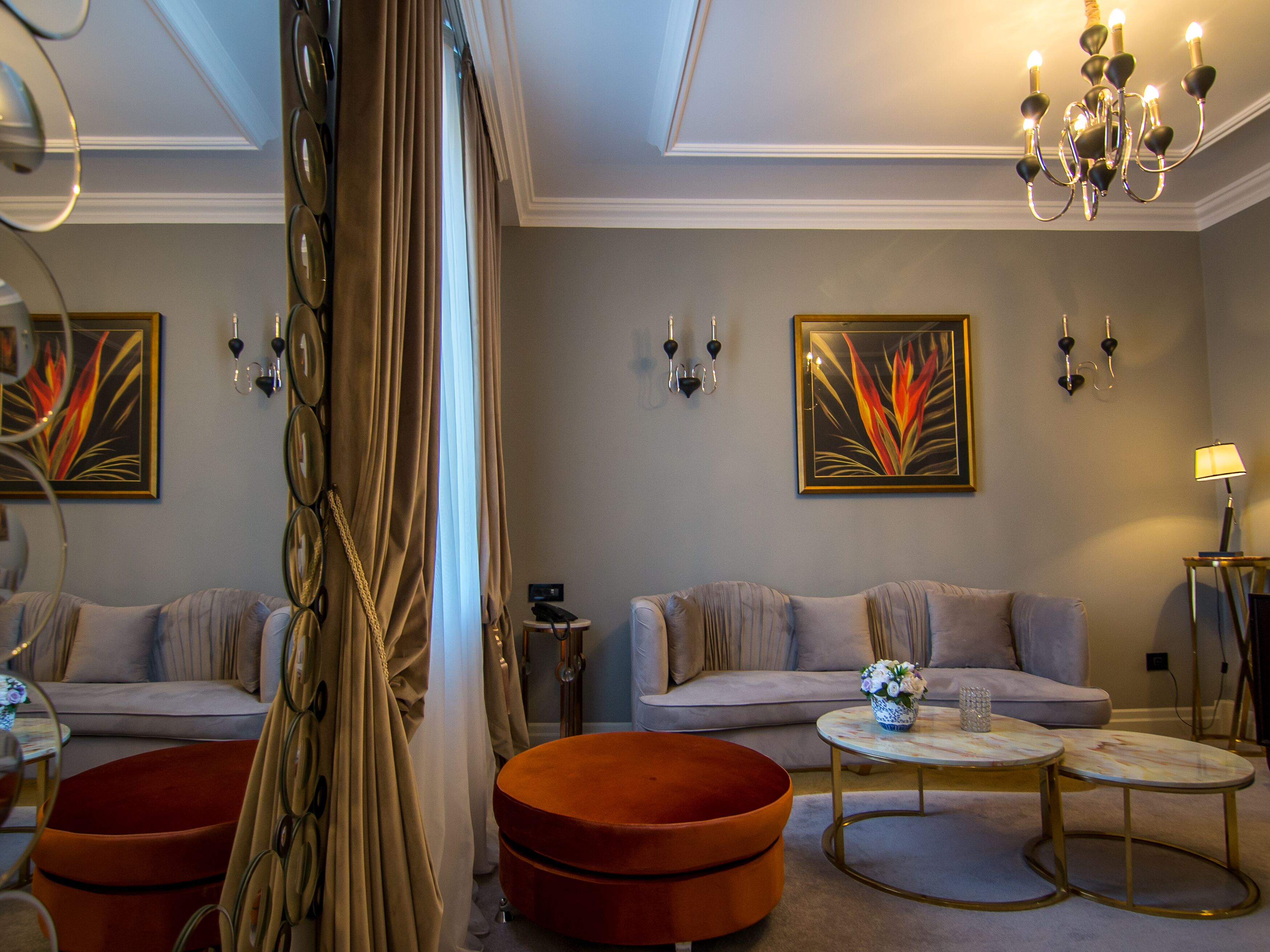 A modern living room with a sofa, ottoman, and coffee table, a chandelier, and wall-mounted artwork.