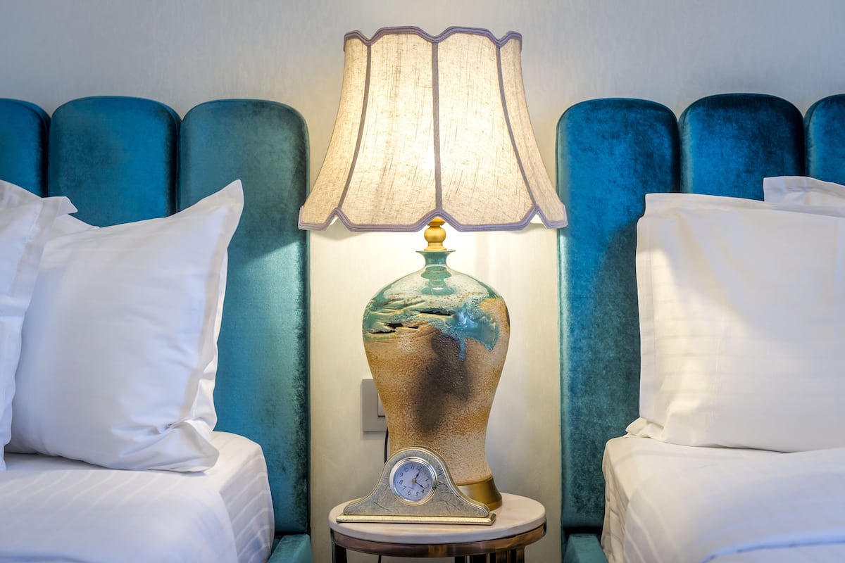 Ein Hotelzimmer mit einem Bett, einem Nachttisch mit Lampe und einer Wand mit blauem Kopfteil.