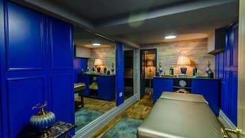 Relax in a stylish room with a large mirror, comfortable bed, and cozy table with a lamp.