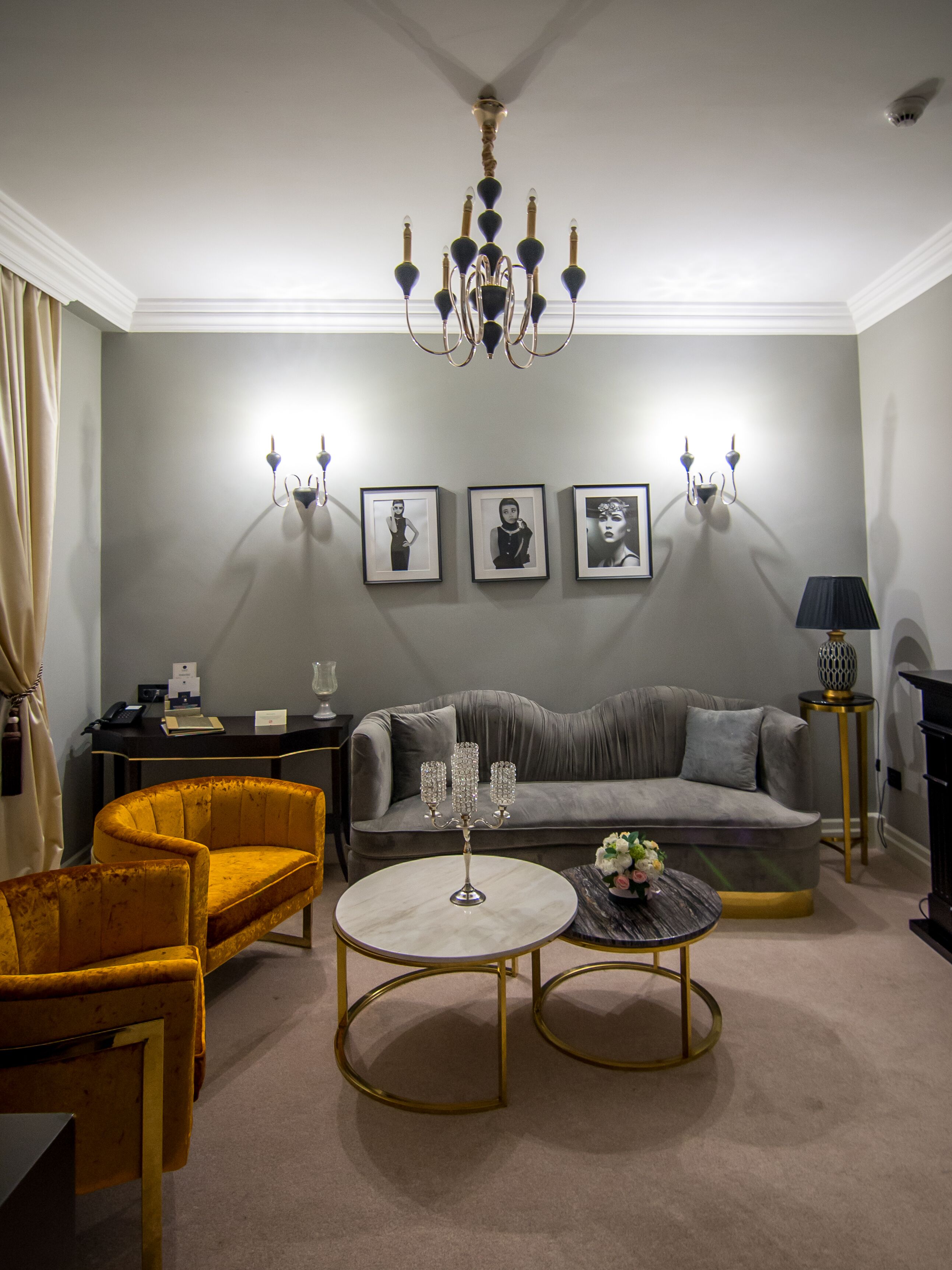 A living room with a grey sofa, two armchairs, a round coffee table, and a chandelier.