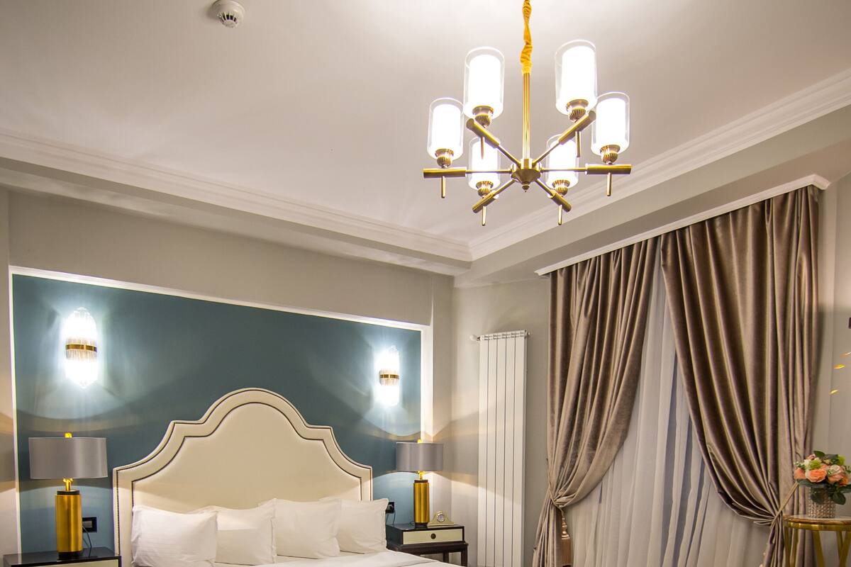 Ein geräumiges Schlafzimmer mit einem großen Bett, einer Kandelaber und einem modernen Kopfteil.