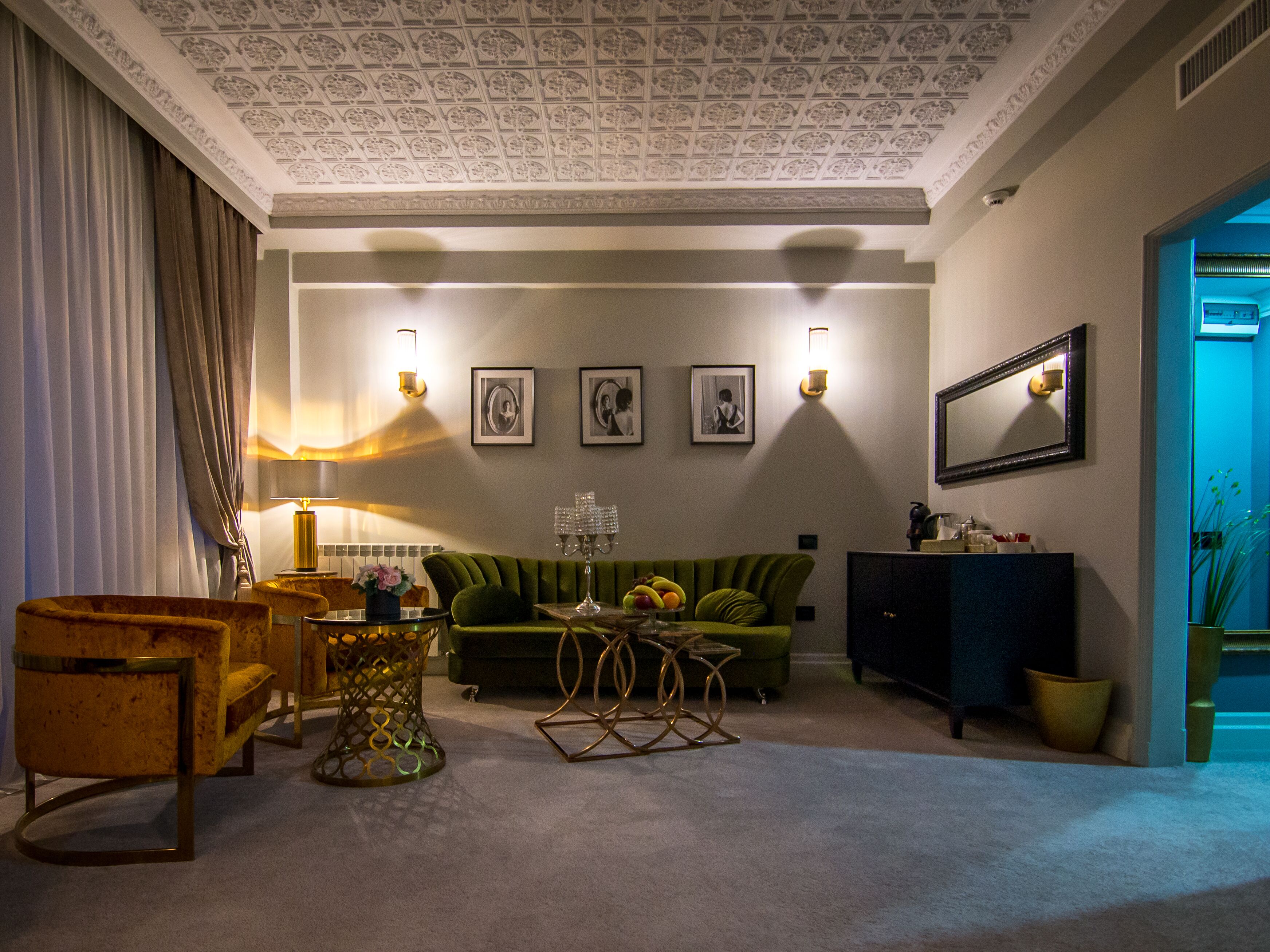 A living room with a green sofa, a wooden armchair, a coffee table with a vase, and a cabinet.