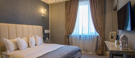 Una habitación de hotel con una cama grande, un candelabro, un escritorio con espejo y un televisor.