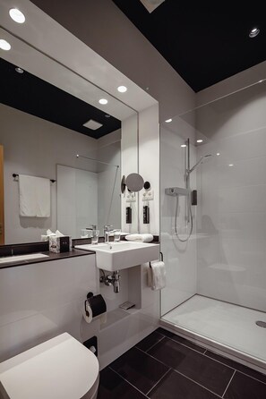 A modern bathroom with a white sink, mirror, and shower.
