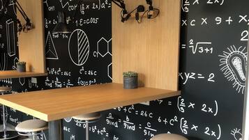 A modern bar area with a wooden table, black stools, and a chalkboard wall filled with scientific equations and diagrams.