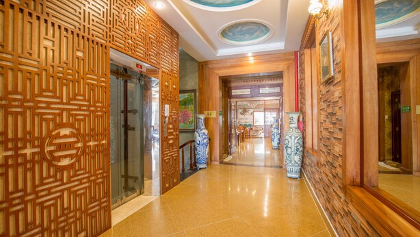A hallway with traditional wooden paneling, a large blue and white vase, and a tiled floor. - Seika Hotel (Ho Chi Minh City)