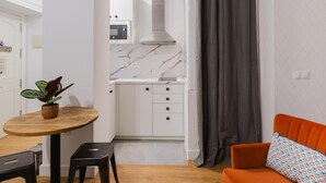 A compact kitchen with white cabinets, a marble backsplash, and a modern microwave. - Casa Armonía, charming apartment in the centre (Málaga)