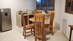 Cozinha compacta com geladeira, fogão e pia. Há uma mesa de jantar com cadeiras.