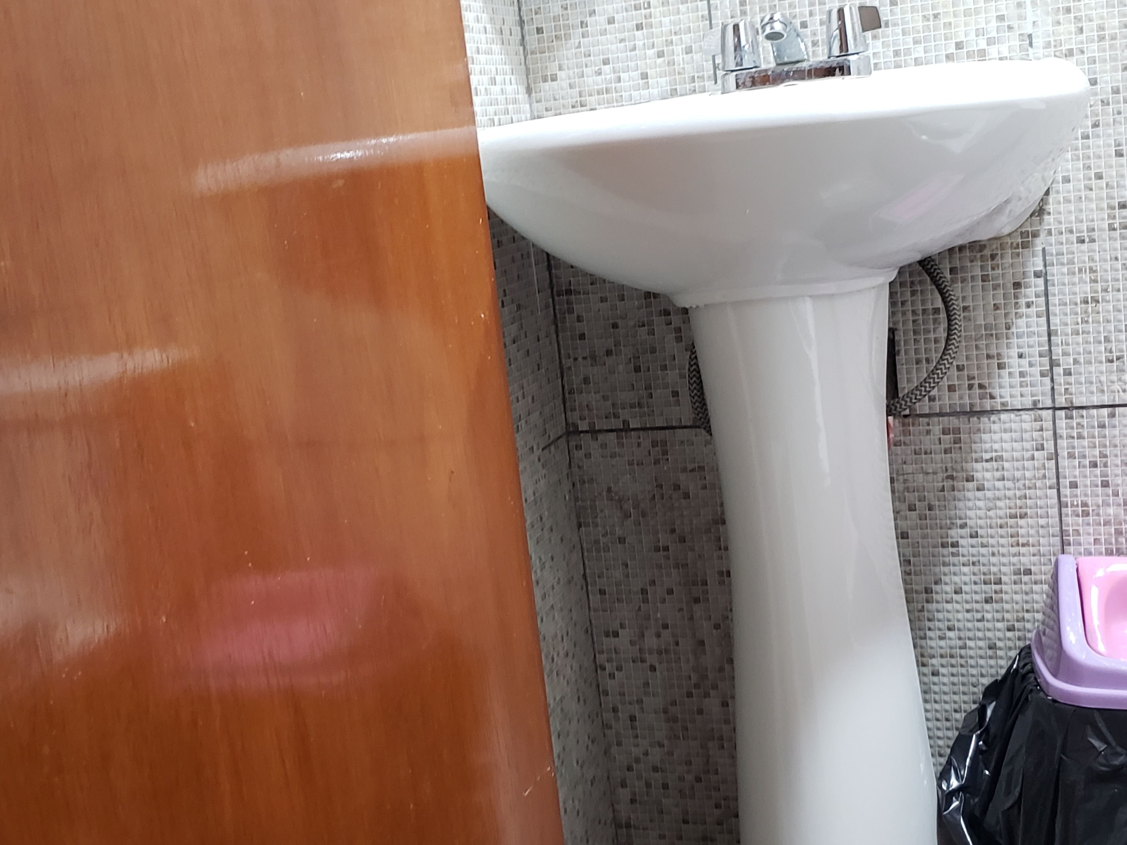 A bathroom with a white sink, tiled walls, and a wooden door.