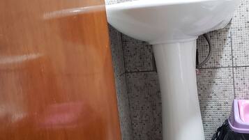 A bathroom with a white sink, tiled walls, and a wooden door.