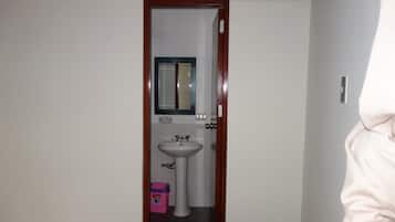 Ein Badezimmer mit einem weißen Waschbecken, einem Spiegel und einer Tür mit Holzrahmen.