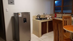 Cozinha compacta com geladeira, fogão a gás, pia e janela com vista.