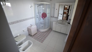 Ein Badezimmer mit Duschkabine aus Glas, Toilette, Bidet und Waschbecken.