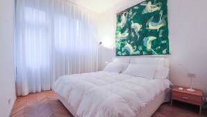 Une chambre à coucher avec un lit, une table de chevet, une lampe et un grand tableau abstrait accroché au mur.