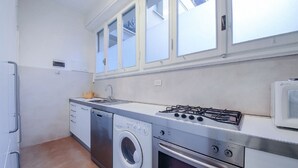 Une cuisine compacte équipée d’un lave-linge, d’un four, d’une cuisinière à gaz et d’un four à micro-ondes.