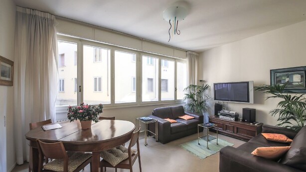 Un salon comprenant une table à manger, un canapé, un téléviseur et des plantes.