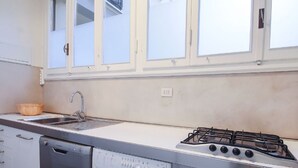 Une cuisine équipée d’un lave-vaisselle, d’un évier, d’une cuisinière et d’une fenêtre située au-dessus de l’évier.