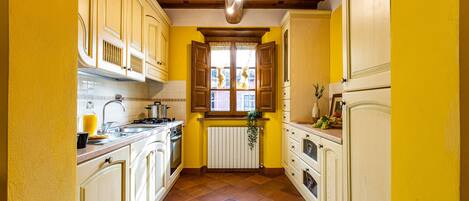 A narrow kitchen with yellow walls, wooden cabinets, and a tiled floor.