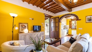 A living room with a sofa, a coffee table, a TV, and a plant.