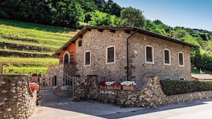 A stone building with a sloped roof, multiple windows, and a gated entrance.