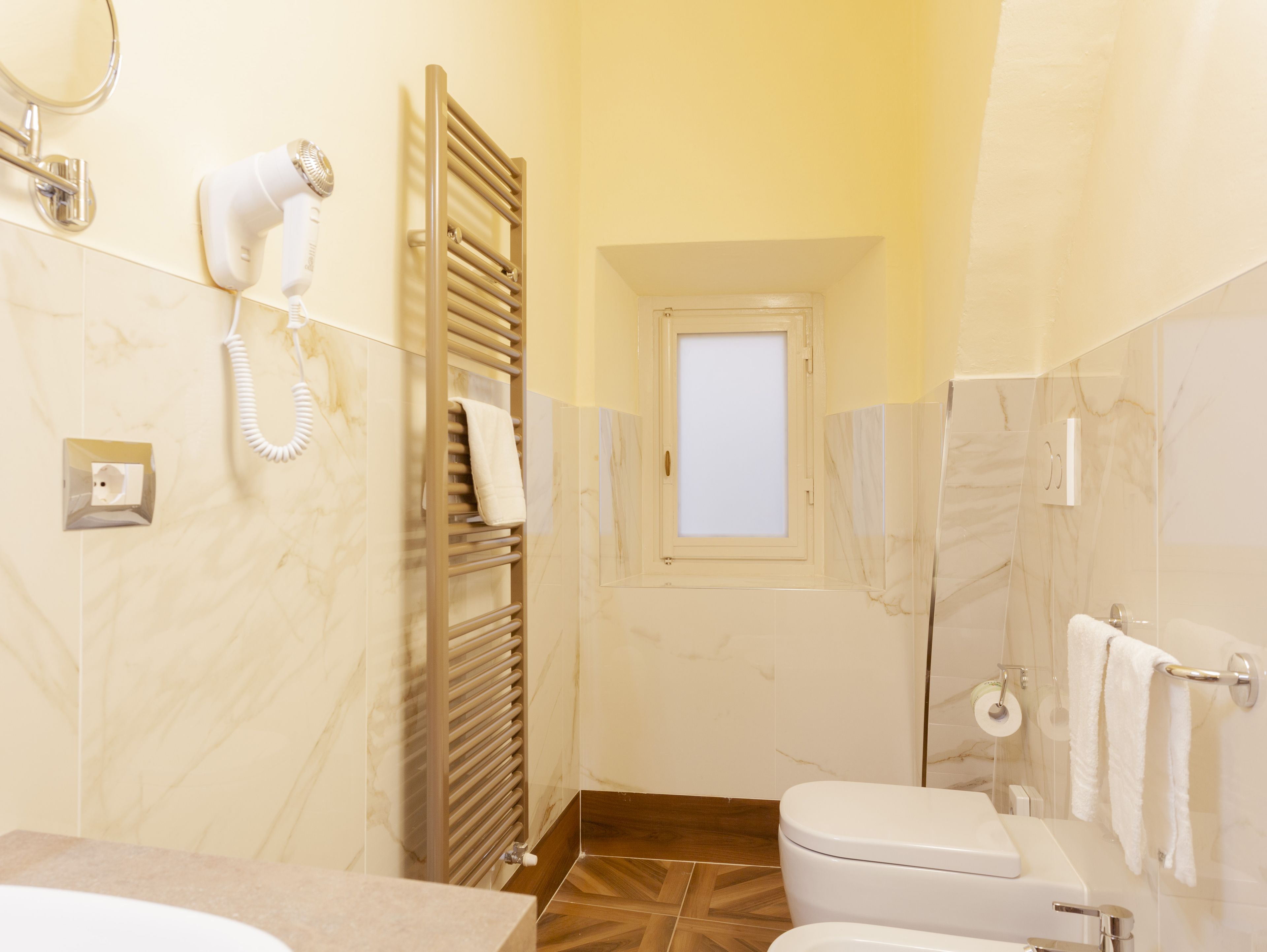 A bathroom with a toilet, a towel rack, a hairdryer, and a mirror.