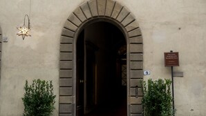 Un bâtiment doté d’une entrée en arc de cercle, d’une petite fenêtre au-dessus de la porte et d’une enseigne indiquant le nom et l’adresse.