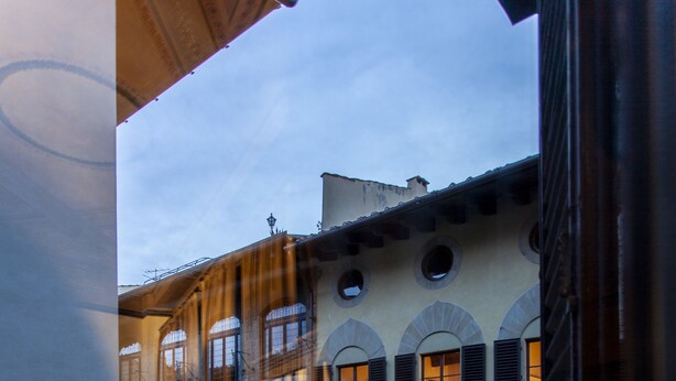 Un immeuble à plusieurs étages, doté de fenêtres en arc de cercle et de balcons, et dont la façade est un mélange de pierre et de crépi.