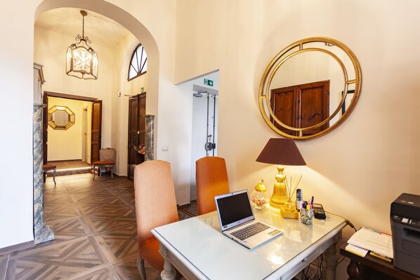 A hotel lobby with a laptop on a table, a mirror, and a lamp.