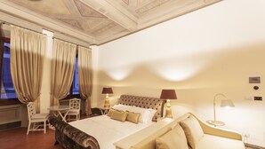 Une chambre d’hôtel avec un grand lit, deux tables de chevet avec des lampes, un canapé et une petite table avec des chaises.