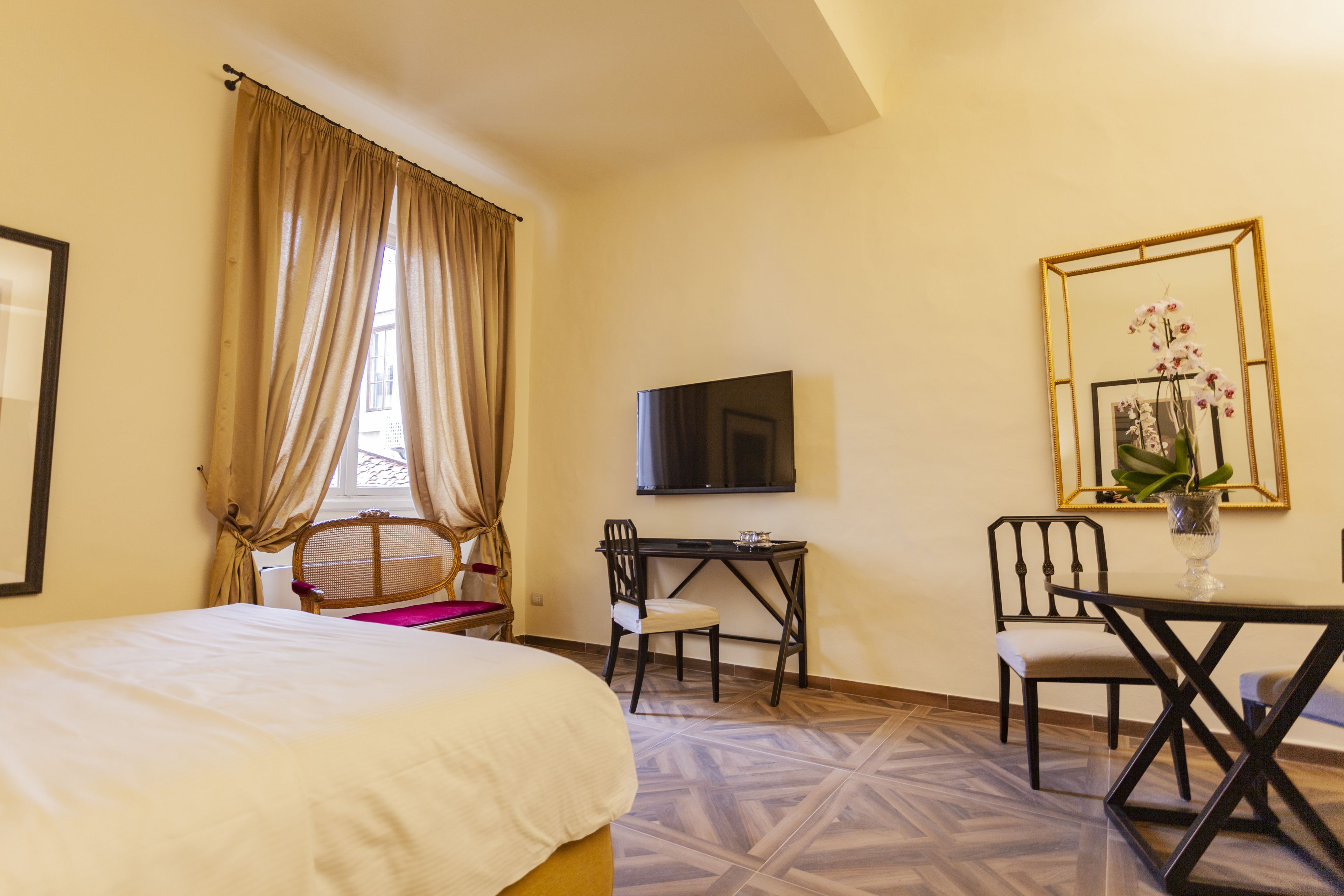 A hotel room with a bed, a desk, a chair, a television, and a mirror.