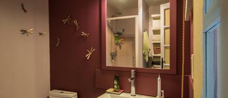 Une salle de bain avec un lavabo blanc, un miroir au-dessus et des toilettes. Des étoiles de mer décoratives sont accrochées au mur.