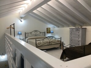 Um quarto com cama, penteadeira, abajur e um quadro na parede.