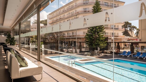 A modern hotel pool area with a glass balustrade, lounge chairs, and a view of the surrounding buildings. - ALEGRIA Mariner - Adults Only (Lloret de Mar)