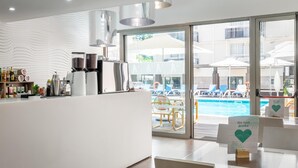 A modern bar area with a coffee machine, bottles, and a view of a pool and lounge chairs. - ALEGRIA Mariner - Adults Only (Lloret de Mar)