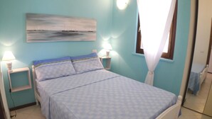 Un dormitorio con una cama, dos mesitas de noche, una lámpara de pared y una ventana con cortinas.