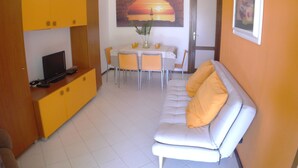 Una sala de estar con sofá, mesa de comedor y televisor.
