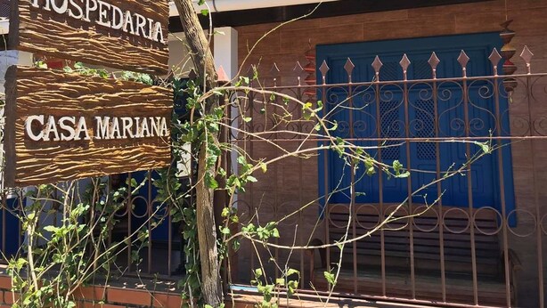 Une pancarte en bois portant les inscriptions « HOSPEDARIA » et « CASA MARIANA », fixée à un arbre.