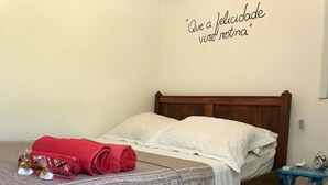 Un lit bien fait, avec du linge de lit blanc et une serviette rouge enroulée sur le côté gauche.