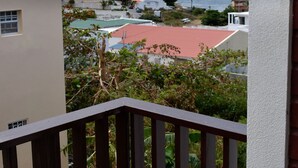 En balkon med udsigt over et boligområde, inklusive huse med røde tage og et vandområde i det fjerne.