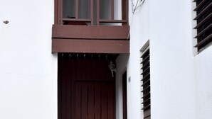 En toetages bygning med en brun trædør og trapper op til en balkon.