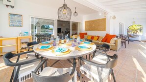 A dining area with round tables, chairs, and a hanging light fixture. - House in quiet and green surrounding where you can disconnect and enjoy family (La Nucia)